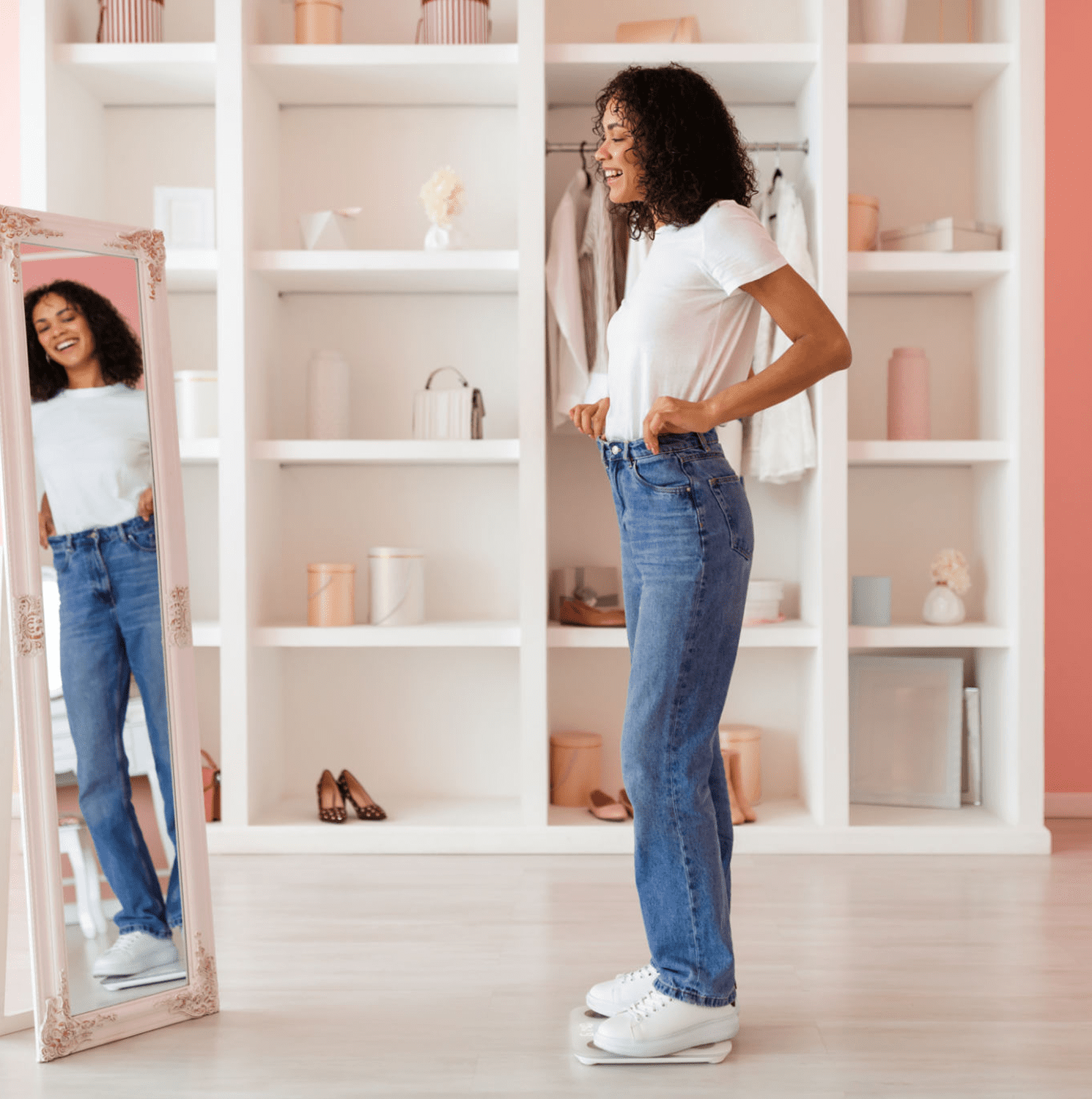 Woman smiling in mirror wearing jeans and sneakers.