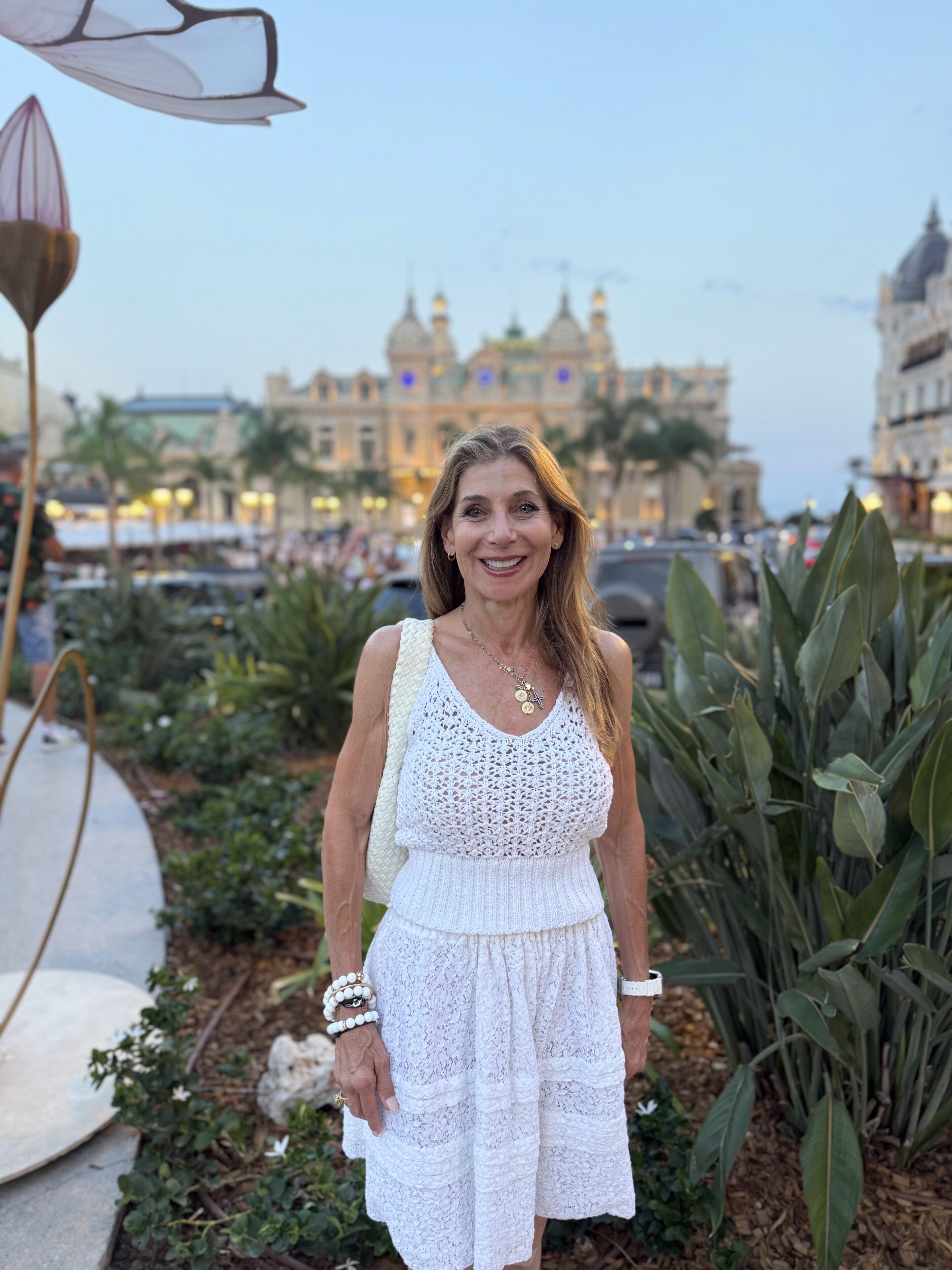Smiling woman in white dress near historic building