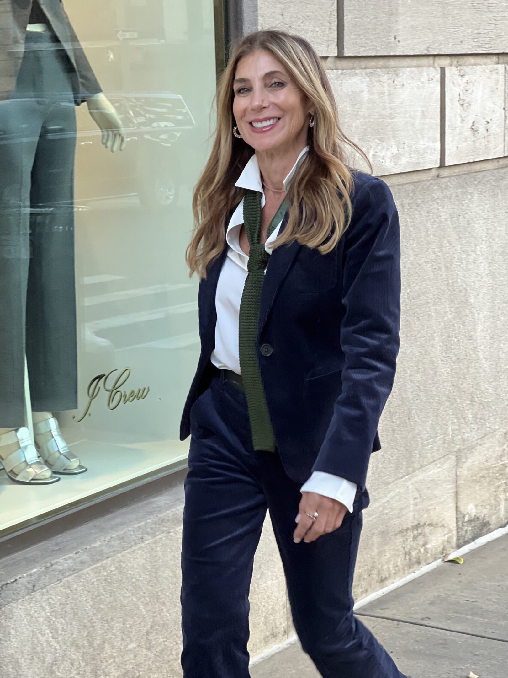 Smiling woman in navy suit with green tie